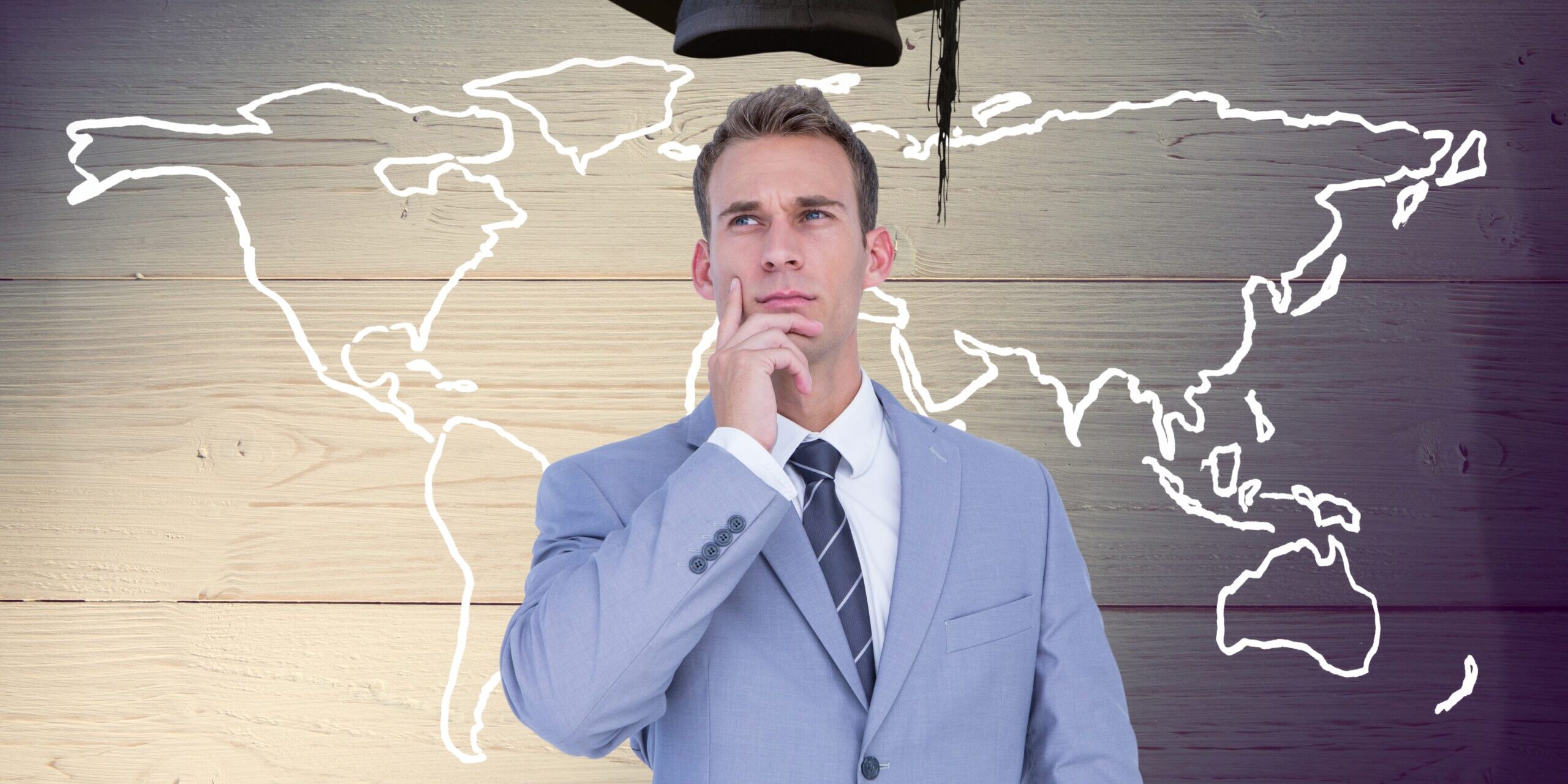 Businessman with mortarboard above head and world map against wooden background